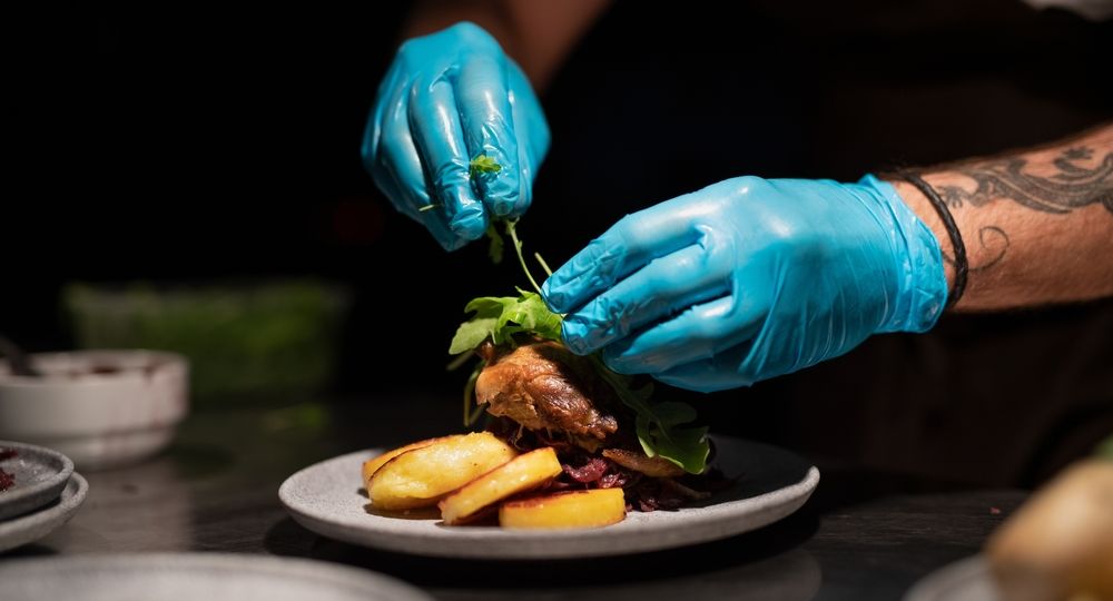 Chef's,Hands,In,Gloves,Serving,And,Decorating,Meal,In,Restaurant
