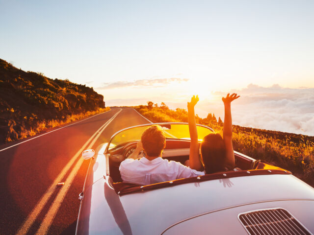 Happy,Couple,Driving,On,Country,Road,Into,The,Sunset,In