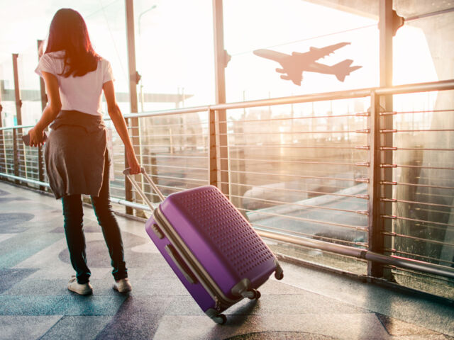 Young,Woman,Pulling,Suitcase,In,Airport,Terminal.,Copy,Space