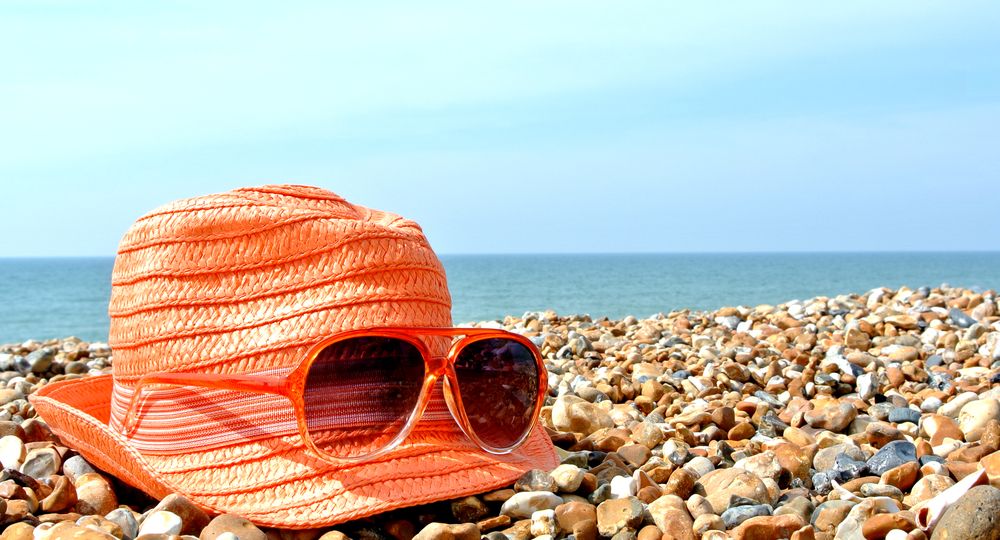 Sunglasses,And,Hat,On,A,Pebbled,Beach