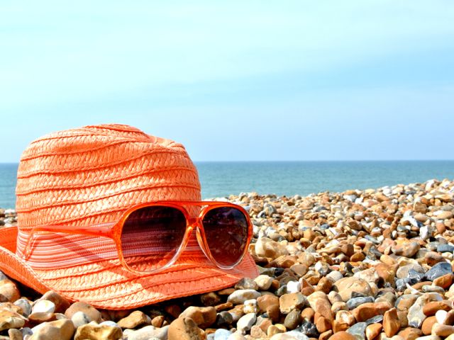 Sunglasses,And,Hat,On,A,Pebbled,Beach