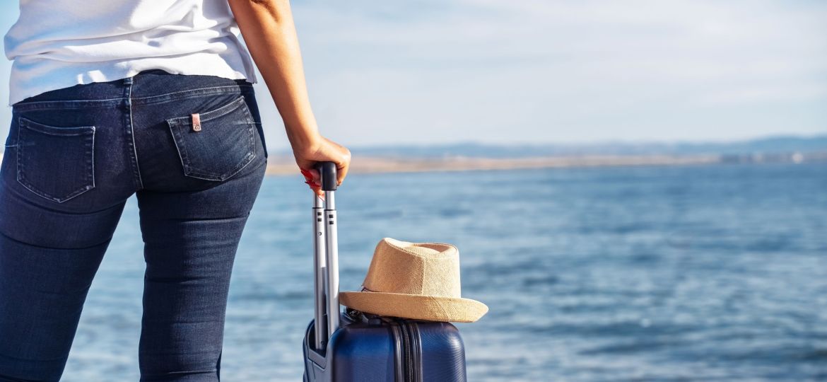 Woman,Gazes,At,The,Ocean,While,Holding,A,Suitcase,With