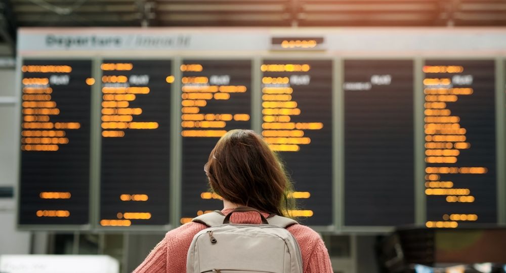 Woman,,Back,And,Airport,With,Flight,Schedule,On,Board,With