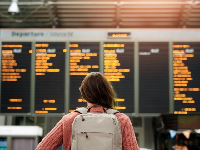 Woman,,Back,And,Airport,With,Flight,Schedule,On,Board,With